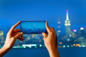 hands holding the phone and capturing the beautiful seanic view of buildings and towers.